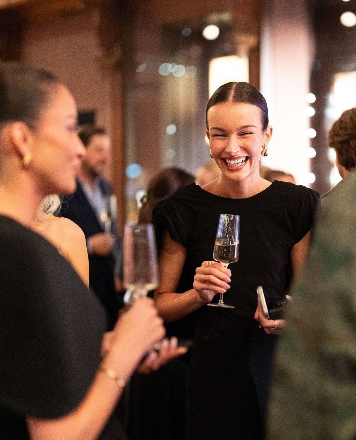 Guests laughing over a glass of champagne at a KPAT event